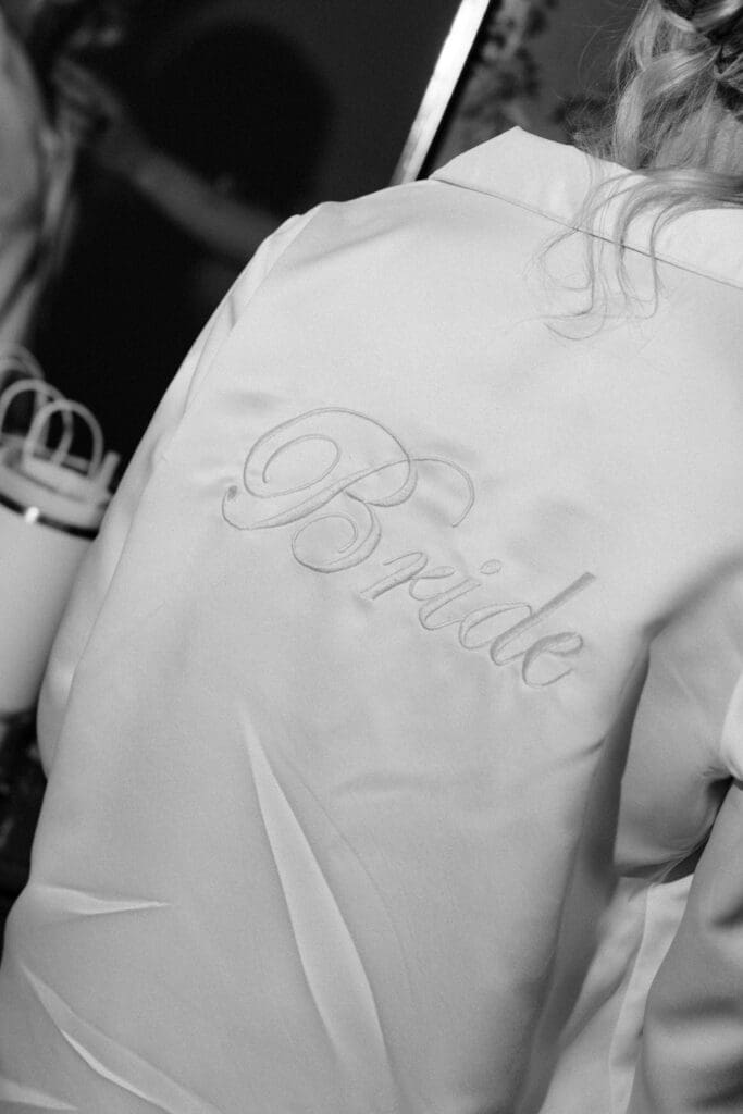 Black and white close-up of bride’s robe during wedding morning preparations.