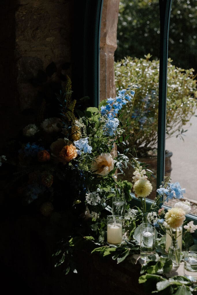 Floral ceremony installation with soft blue and peach flowers arranged beside the window at Broxmouth Courtyard.