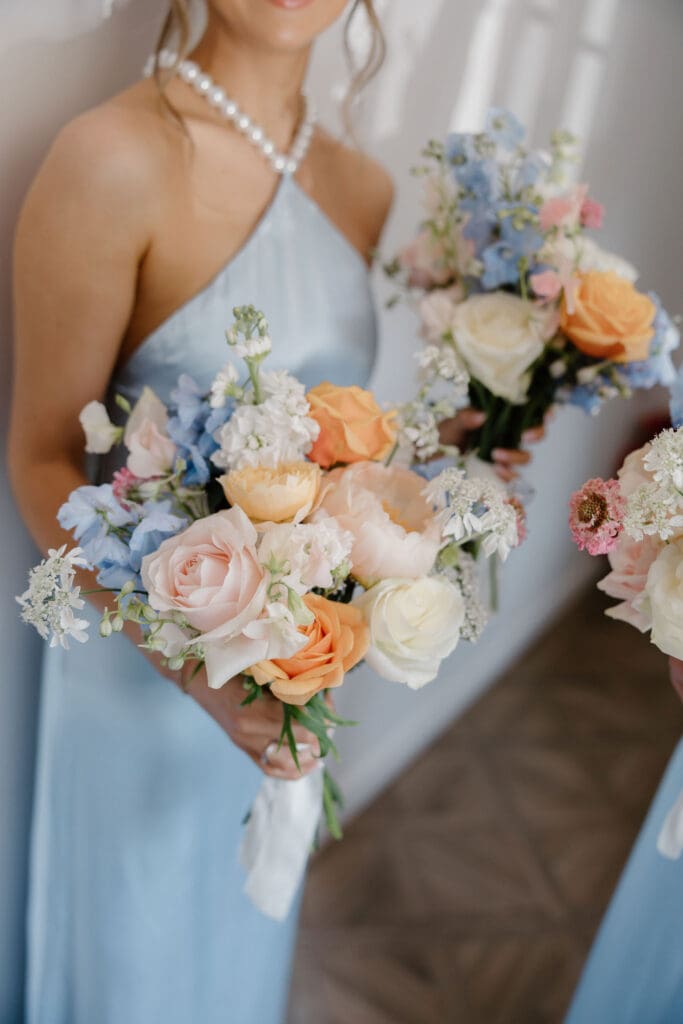 Bridesmaid holding pastel wedding bouquet during morning preparations at Broxmouth Courtyard.