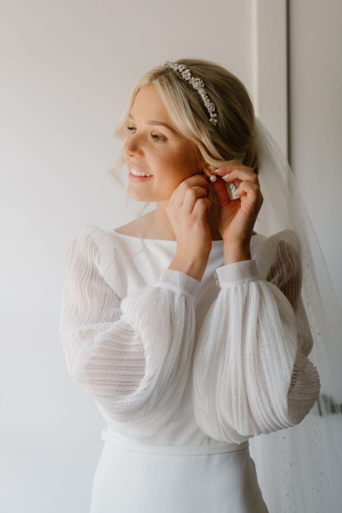 Bride fastening earrings during morning preparations