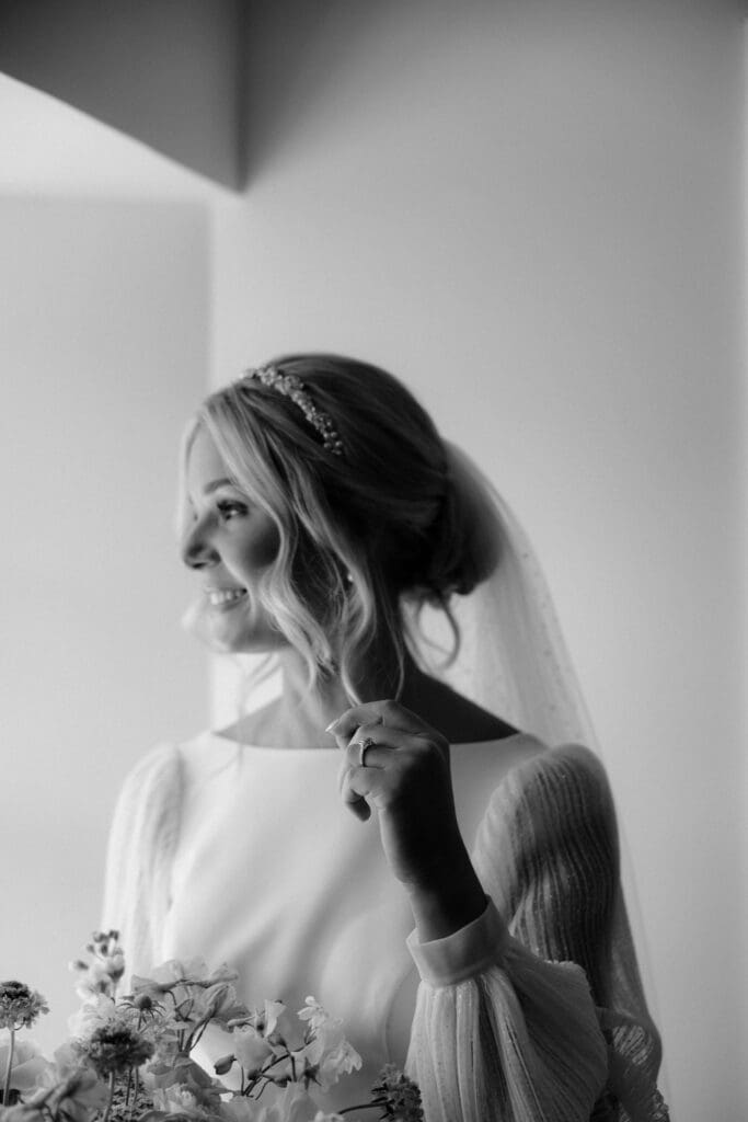 Black and white portrait of bride smiling during quiet wedding morning moment.