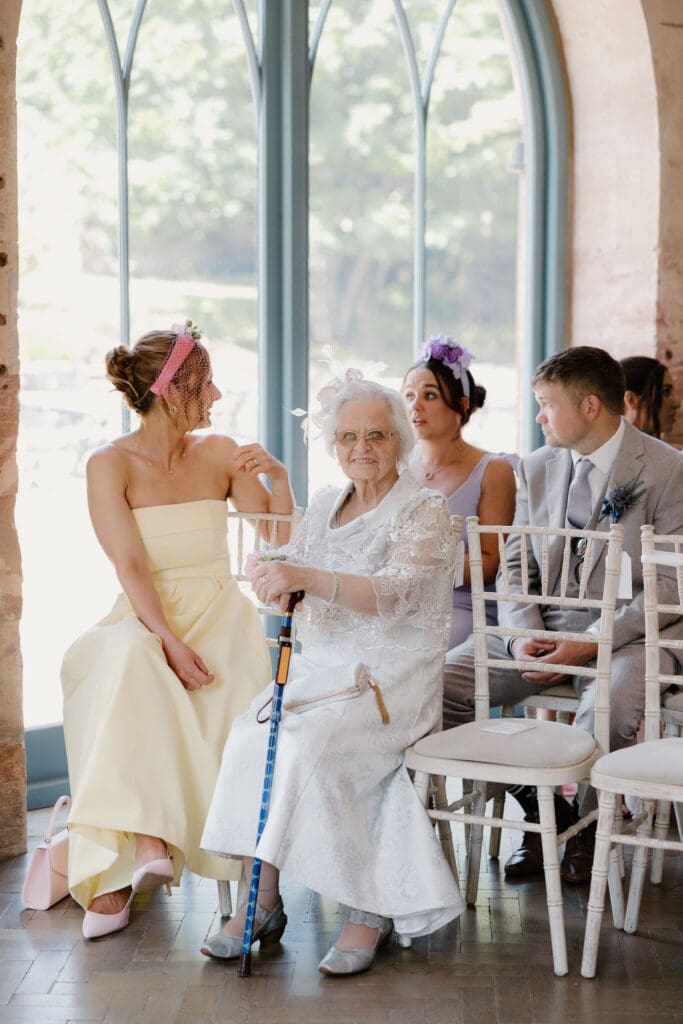 Wedding guests seated inside Broxmouth Courtyard, including grandmother smiling during the ceremony.