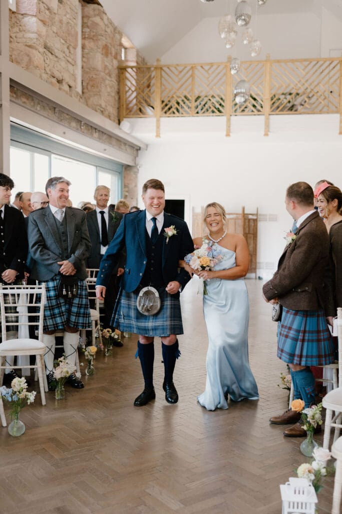Bridesmaid and groomsmen walking down the aisle together at Broxmouth Courtyard.