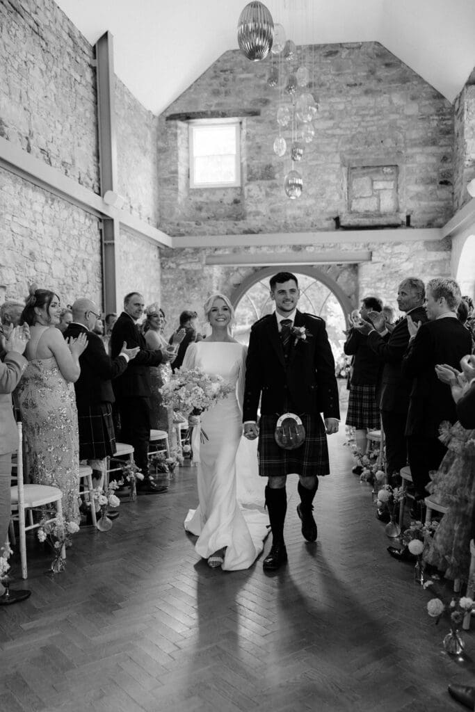 Bride and groom walking back up the aisle together after the ceremony at Broxmouth Courtyard.