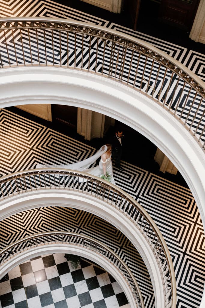 Bride and groom walking on the spiral staircase at The Edinburgh Grand during her wedding day