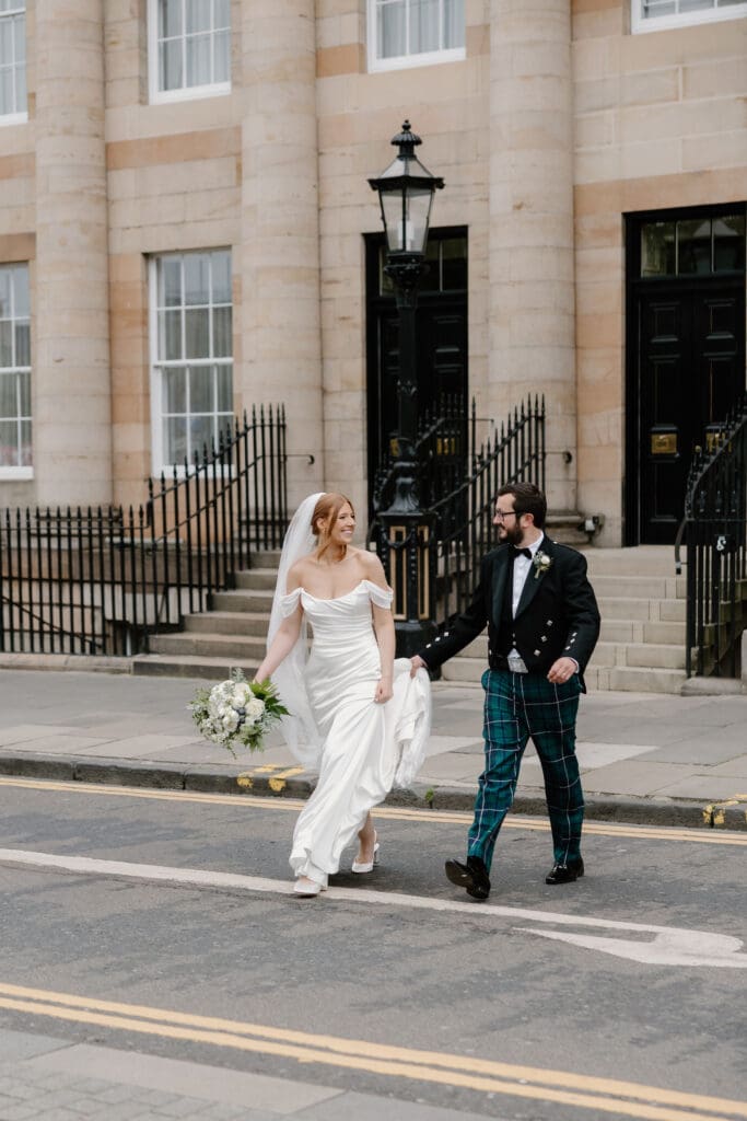 Bride and groom walking through Edinburgh city centre outside The Edinburgh Grand on their wedding day
